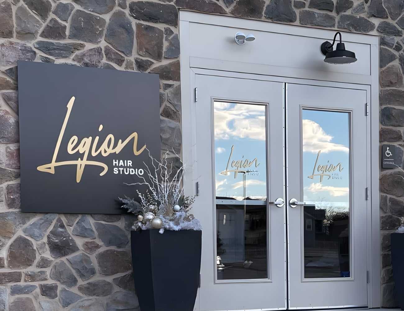 Legion Hair Studio entrance with decorative planters and stone façade.