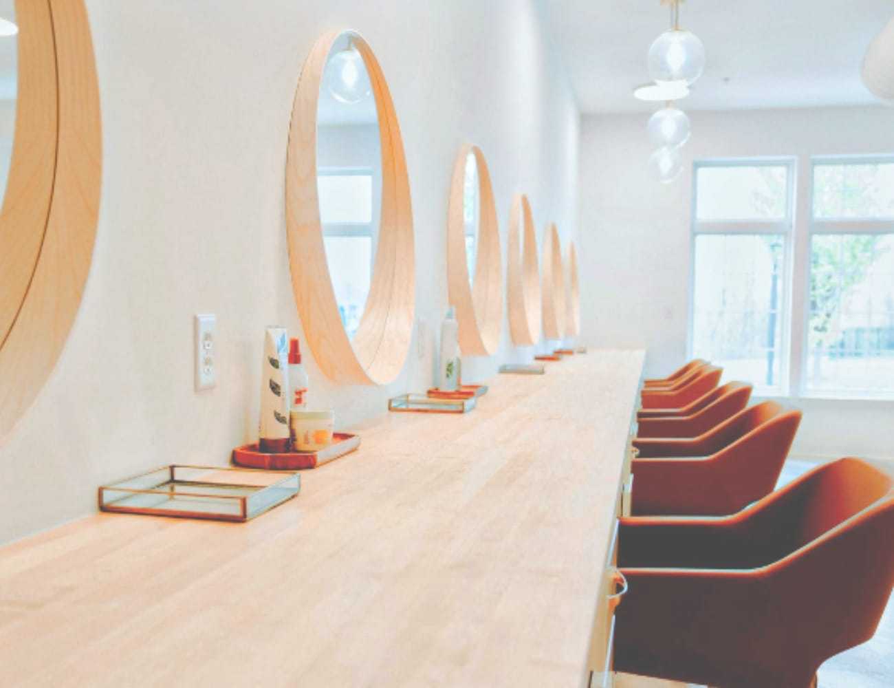 Modern salon interior with round mirrors and wooden furnishings.