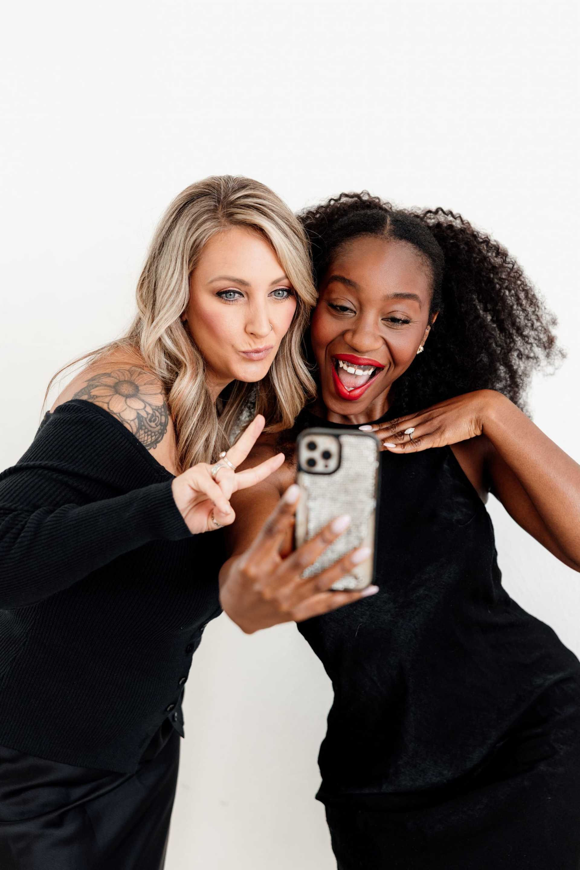 Two women happily taking a selfie together in stylish outfits.
