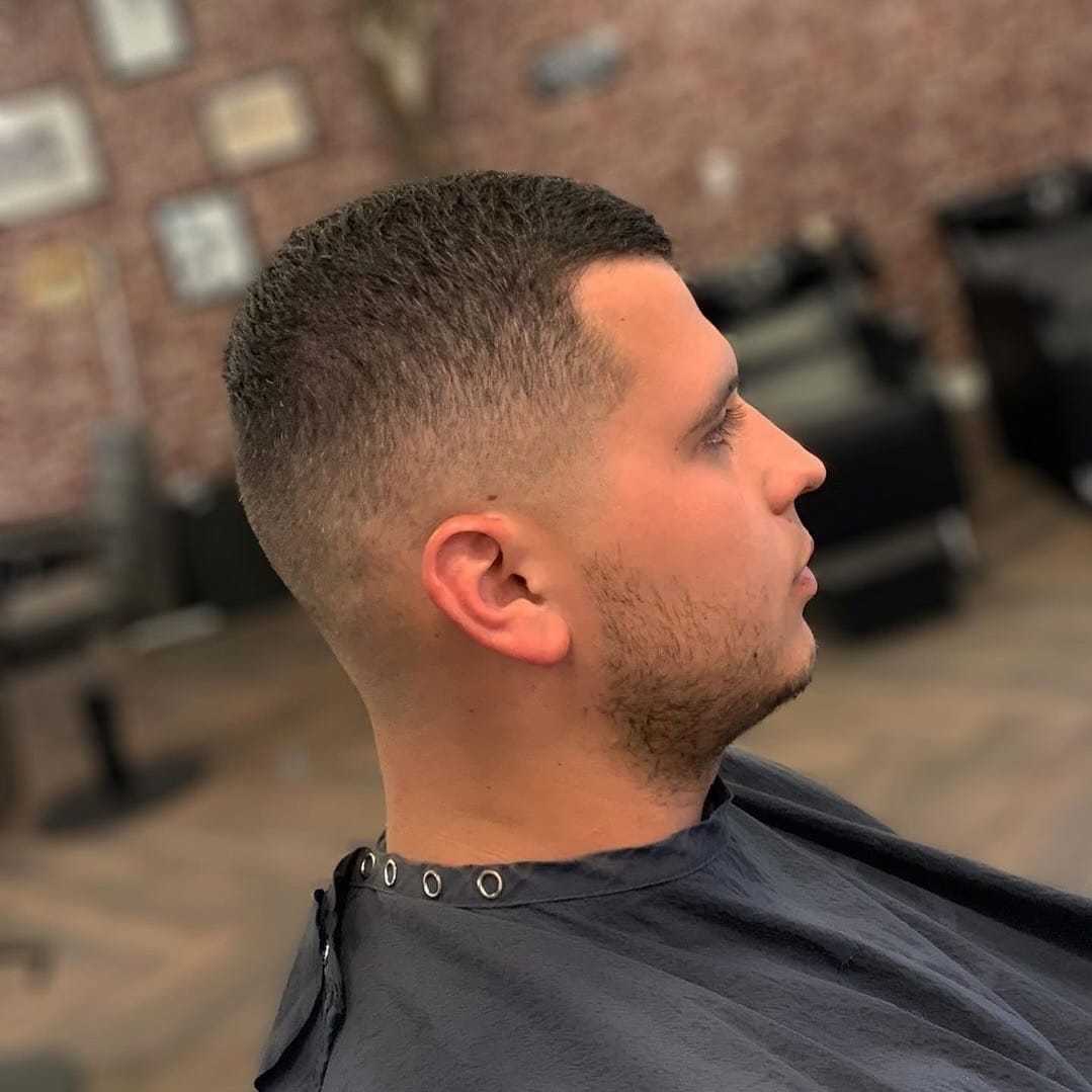 Man with short haircut sitting in a barber chair in a modern barbershop.